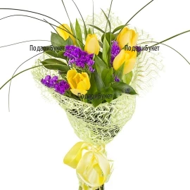 Classical spring bouquet of yellow tulips and generous greenery, arranged in a colorful wrap and tied with a ribbon.